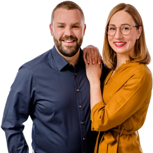 Kristin und Marcus Nartschik nebeneinander vor weißem Hintergrund, beide lächeln in die Kamera, sie legt ihm die Hand auf die Schulter.